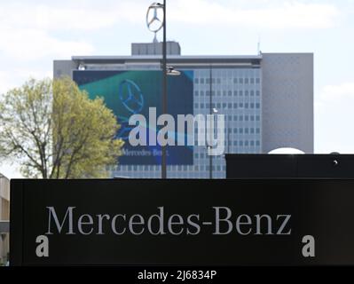 Stuttgart, Deutschland. 28. April 2022. 28. April 2022, Baden-Württemberg, Stuttgart: Das Mercedes-Benz Firmenzeichen steht am Werkseingang des Hauptwerks. Die Zentrale ist im Hintergrund. Die Jahreshauptversammlung des Automobilkonzerns findet am 29. April statt. Foto: Bernd Weißbrod/dpa Quelle: dpa picture Alliance/Alamy Live News Stockfoto