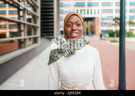 Charmante schwarze Frau im muslimischen Kopftuch, die auf der Straße steht Stockfoto