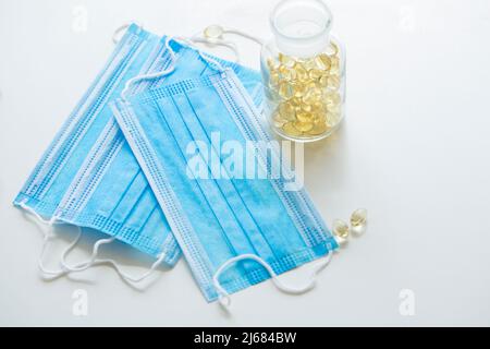 Blaue Einwegmasken, Softgel oder Kapsel der öligen Medizin und Medizin-Flaschen - Stock Foto Stockfoto