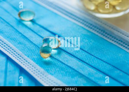 Blaue Einwegmasken, Softgel oder Kapsel der öligen Medizin und Medizin-Flaschen - Stock Foto Stockfoto