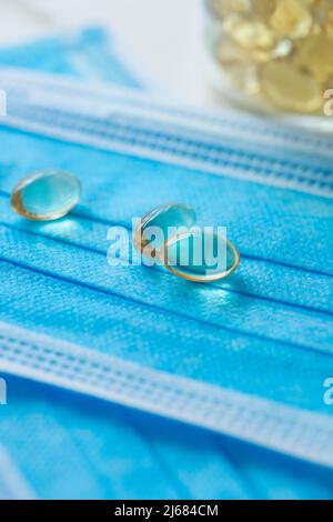 Blaue Einwegmasken, Softgel oder Kapsel der öligen Medizin und Medizin-Flaschen - Stock Foto Stockfoto