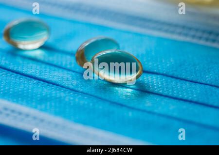 Blaue Einwegmasken, Softgel oder Kapsel der öligen Medizin und Medizin-Flaschen - Stock Foto Stockfoto