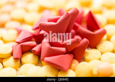 Rote herzförmige Origami-, gelbe und orange Pillen auf weißem Hintergrund - Stock Foto Stockfoto