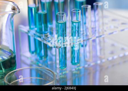 Ordentlich angeordnete Reagenzröhrchen mit blauem Reagenz im Chemielabor mit Becher und Petri-Dishe - Stock Photo Stockfoto
