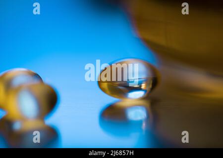 Weiche Kapseln in Blau leuchten auf silbernem Hintergrund - Stock Foto Stockfoto