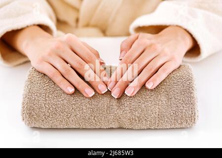 High Angle of Crop anonyme weibliche Klientin im Bademantel zeigt neuen Französisch Nagellack auf Handtuch in Beauty-Studio Stockfoto