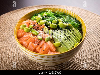 Von oben aus eine köstliche Schüssel mit frischem Gemüse und Lachs auf den Tisch im Café gelegt Stockfoto