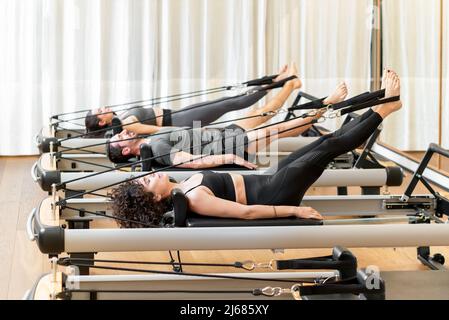 Klasse von verschiedenen Menschen, die die hundert Pilates auf Reformer Betten in einem Fitnessstudio in einem gesunden aktiven Lebensstil Konzept trainieren Stockfoto