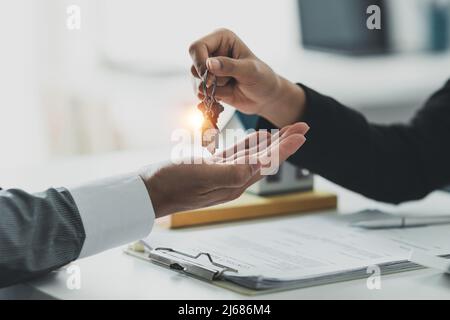Nahaufnahme Geschäftsmann oder Immobilienmakler geben Hausschlüssel nach der Unterzeichnung Vereinbarung für den Kauf von Haus. Bankmanager und Immobilienkonzept. Stockfoto