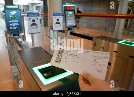 Hamburg, Deutschland. 28. April 2022. 28. April 2022, Hamburg: Eine Frau hält eine Bordkarte neben dem biometrischen Gesichtsfelderkennungssystem vor der Sicherheitskontrolle im Abflugbereich des Hamburger Flughafens hoch. Der neue Service steht Star Alliance-Passagieren (Österreich, Schweiz und Lufthansa) zur Verfügung, die am Miles & More Treueprogramm teilnehmen. Passagiere erhalten kontaktlosen Zugang zum Sicherheitskontrollpunkt und zum Boarding. Eine Bordkarte oder ein Smartphone müssen nicht mehr vorgelegt werden. Foto: Marcus Brandt/dpa Quelle: dpa picture Alliance/Alamy Live News Stockfoto