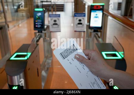 Hamburg, Deutschland. 28. April 2022. 28. April 2022, Hamburg: Eine Frau hält eine Bordkarte vor dem biometrischen Gesichtsfelderkennungssystem an der Sicherheitskontrolle im Abflugbereich des Hamburger Flughafens. Der neue Service steht Star Alliance-Passagieren (Österreich, Schweiz und Lufthansa) zur Verfügung, die am Miles & More Treueprogramm teilnehmen. Passagiere erhalten kontaktlosen Zugang zum Sicherheitskontrollpunkt und zum Boarding. Eine Bordkarte oder ein Smartphone müssen nicht mehr vorgelegt werden. Foto: Marcus Brandt/dpa Quelle: dpa picture Alliance/Alamy Live News Stockfoto