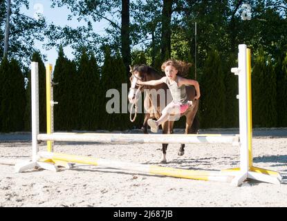 Mädchen springt mit ihrem Pony über die Hürde Stockfoto