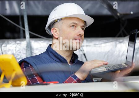 Professioneller Techniker mit pc in der Decke Stockfoto