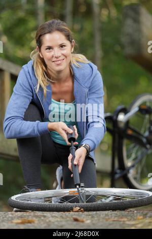 Frau pumpt einen Fahrradreifen mit einer kleinen Handpumpe auf Stockfoto
