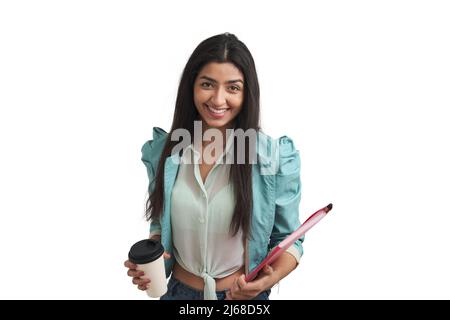 Junge Venezolanerin, die mit Kaffee und Ordner lächelt, isoliert. Stockfoto