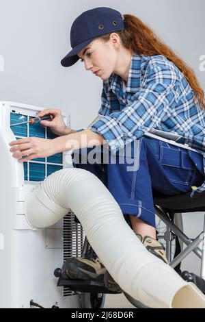 Eine behinderte Technikerin, die an der Klimaanlage arbeitet Stockfoto