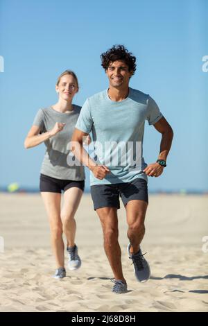 Glückliches Paar, das zusammen am Wasser läuft Stockfoto