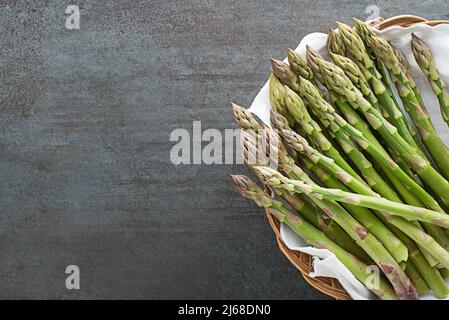 Spargel. Frischer Spargel. Eingelegter grüner Spargel im Korb. Grüne Spargelbündel auf grauem Tisch Nahaufnahme, Draufsicht- Bild Stockfoto