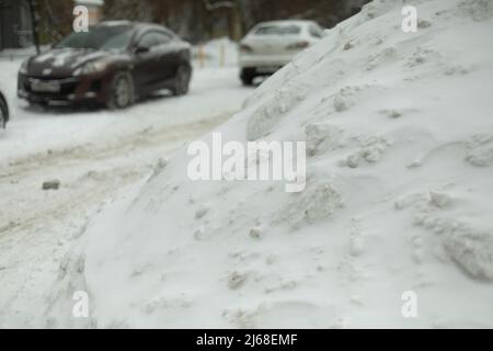 Schnee auf dem Parkplatz. Schneeverwehung auf der Straße. Nach dem Schneesturm. Eisrutsche. Stockfoto