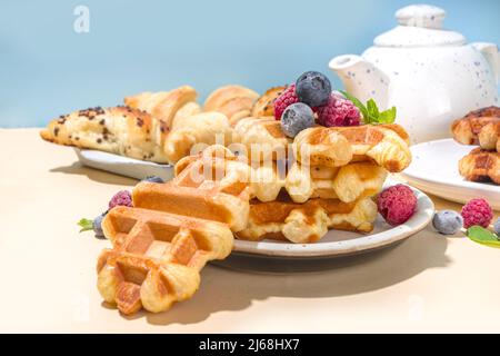 Modernes Dessert-Croffle: Eine Mischung aus Croissants und Waffeln, Waffeleisen-Pfanne mit Waffeleisen, Beerenfrüchten und Schokolade Stockfoto