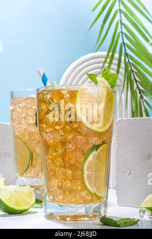 Cuba Libre, langer Eisteecocktail mit starkem Alkoholgetränk, Cola, Limette und Eis in zwei Gläsern, kalter Longdrink-Mocktail auf hellblau gefliestem Rücken Stockfoto