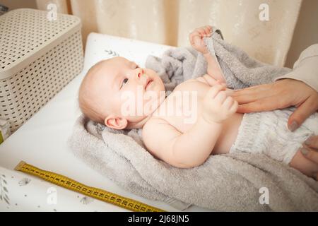 Mutter misst das Wachstum des Kindes, in Gefangenschaft Tisch, medizinische Untersuchung. Entwicklung, Höhe. Stockfoto