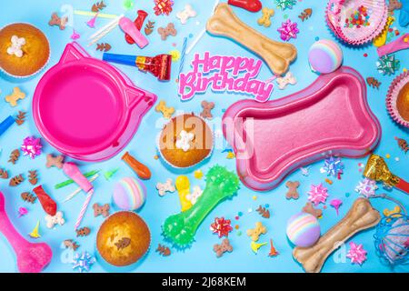 PET Happy Birthday Hintergrund mit Set Hund und Katze Snack, Futter und Spielzeug, Knochen und Katze geformte Schale, Geburtstag Cupcakes mit Happy Birthday Kerzen und ein Stockfoto