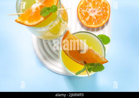 Klassischer Sommer-Mimosas-Cocktail mit Orangensaft auf hellblauem Hintergrund. Sommerliches Bar-Menü mit Kopierbereich Stockfoto