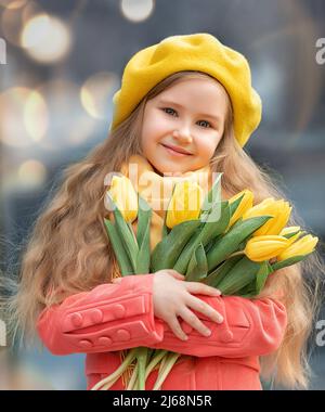 Porträt eines glücklichen Mädchens mit einem Strauß gelber Tulpen auf einem Spaziergang im Frühjahr. Blumen zum Internationalen Frauentag. Stockfoto