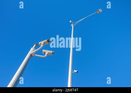 Überwachungskameras und Straßenlaterne, isoliert gegen einen blauen Himmel Stockfoto