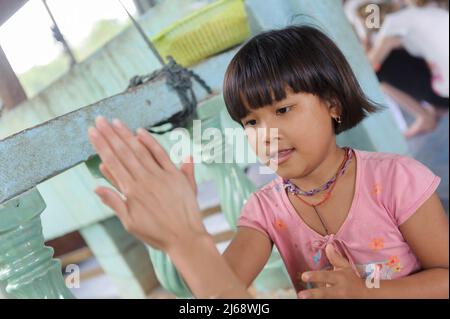 Eine freiwillige Studentin, die im Kinderhaus in Sangkhlaburi ein Spiel mit einem jungen Mädchen spielt, das mit der Hand klatscht. Kanchanaburi. Thailand Stockfoto