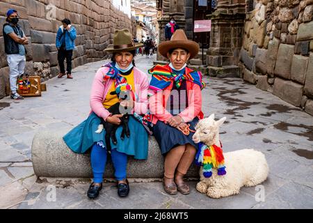 Zwei Indigene Frauen In Traditioneller Tracht Posieren Mit Ihren Haustieren Im Historischen Zentrum Von Cusco, Provinz Cusco, Peru. Stockfoto