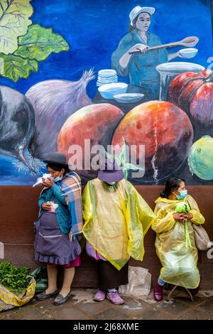 Eine kleine Gruppe peruanischer Frauen, die während Einer Regendusche auf der Straße stehen, Cusco, Provinz Cusco, Peru. Stockfoto