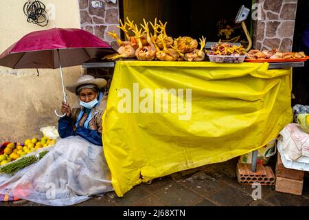 Eine ältere Frau schützt vor dem Regen auf Einem Markt in der Cusco Straße, Cusco, Provinz Cusco, Peru. Stockfoto