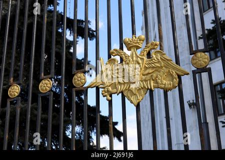 Blick durch den Metallzaun mit doppelköpfigen Adler zum russischen Verteidigungsministerium in Moskau Stockfoto