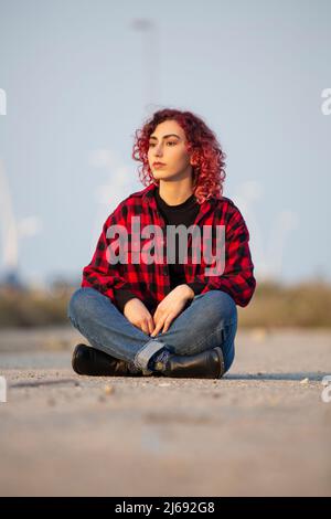 Frau, die auf der Straße sitzt und wegschaut Stockfoto