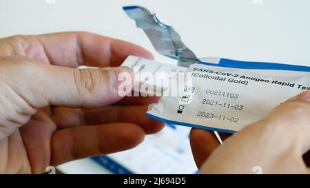 Der Mann reicht eine sterile Packung mit Coronavirus-Antigen-Test zur Selbstdiagnose aus Stockfoto