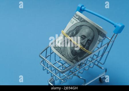 In einen Schlauch gerollte Dollars liegen in einem Einkaufskorb. Stockfoto