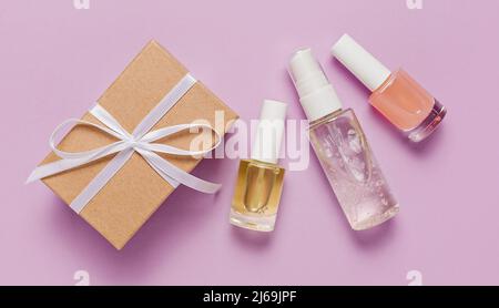 Bio-Kosmetik und Geschenke für den Urlaub. Flach liegend, Draufsicht klare Glas-Pumpe Flasche, Pinsel-Glas, feuchtigkeitsspendende Serum-Glas auf einem violetten Hintergrund. Nat Stockfoto