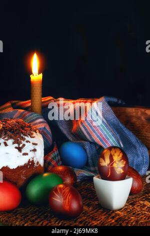 Der Osterfeiertag, Hühnereier in den traditionellen Farben gemalt, kulich, festlicher Kuchen, Kirchenkerzen. Stockfoto