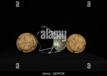 Zwei traditionelle Sektkorken und ein Käfig aus einem einzigen Draht, isoliert auf schwarzem Hintergrund Stockfoto