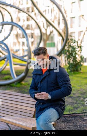 Attraktiver junger Mann mit seinem Smartphone Stockfoto