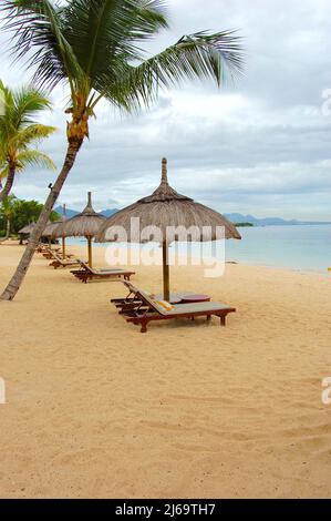 Sonnenliegen unter einem Sonnenschirm am Strand im indischen Ozean in mauritius Stockfoto