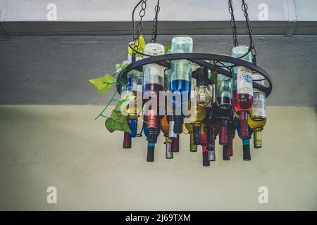 San Salvador, El Salvador - 29. Januar 2022: Aufgehängte Lampe an einer Decke aus Weinflaschen, die kopfüber aufgehängt und mit einem Kronleuchter befestigt ist Stockfoto