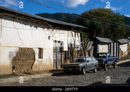 Juayua, El Salvador - 29. Januar 2022: Blick auf eine Straße in einer Stadt in El Salvador mit zerfallenden Gebäuden und beschädigten Autos Stockfoto