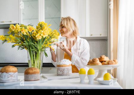 Eine Frau mit ostergebäck und einem Blumenstrauß aus gelben Blumen. Stockfoto