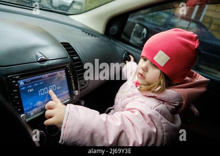 Ein kleines Mädchen wechselt den Radiosender, während es im Auto Musik  hören kann. Hören des Radios im Auto. Automatische Musik Stockfotografie -  Alamy
