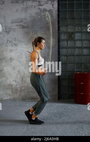 Junge Frau tut springen Seil Aufwärmen Übung vor Boxen Match vertikalen Seitenansicht Schuss Stockfoto