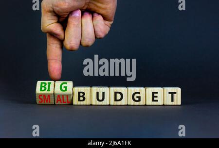 Großes oder kleines Budgetsymbol. Geschäftsmann dreht Holzwürfel und ändert Wörter kleines Budget zu großes Budget. Schöne graue Tabelle grauen Hintergrund, Kopie sp Stockfoto