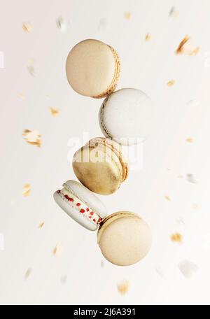 Weiße, gelbe, goldene Macaronkeks. Bunte, süße kleine französische Makronen-Kuchen. Hellbeige unscharfer Hintergrund mit gebrochenen Makaronschnitten, Bits, gebissenen Teilen. Fünf Kekse in der Mitte des Fotos Stockfoto